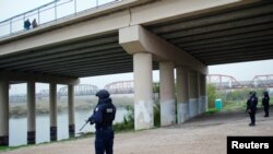 Petugas polisi federal Meksiko berdiri di tepi Rio Bravo dekat jembatan yang menghubungkan Eagle Pass, Texas, dengan Piedras Negras, di Piedras Negras, Meksiko, 10 Februari 2019. (Foto: Reuters)