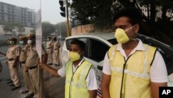 Volunteers and policemen wear pollution masks and stand at a busy crossing with the banner saying obey odd and even, remove pollution, in New Delhi, India, Monday, Nov. 4, 2019. (AP Photo/Manish Swarup)