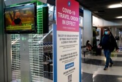 A traveler walks through Terminal 3 as a COVID-19 travel order sign is displayed at O'Hare International Airport in Chicago, Sunday, Nov. 29, 2020. Friday's total of new cases is the next-to-lowest daily number in the past 12 days, but Illinois…