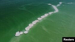 An aerial view shows beach-goers standing on salt formations in the Dead Sea near Ein Bokeq, Israel.