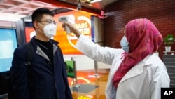 ស្ត្រី​បម្រើការ​នៅ​អាកាសយានដ្ឋាន ​Shahjalal ក្នុង​ទីក្រុង​ដាកា ប្រទេស​បង់ក្លាដែស បាន​វាស់​កម្ដៅ​ក្នុង​ខ្លួន​អ្នក​ដំណើរ​ម្នាក់​ពី​ទីក្រុង​ប៉េកាំង ប្រទេស​ចិន រក​វីរុស​កូរ៉ូណា​ថ្មី ថ្ងៃ​ទី​២៩ ខែ​មករា ឆ្នាំ២០២០។​