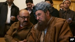 Irfan Sadiqui, kiri, pemimpin tim pemerintah bicara pada imam pro-Taliban Maulana Samiul Haq sebelum konferensi pers di Islamabad.
