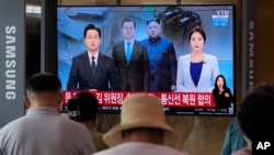 A TV shows a file image of North Korean leader Kim Jong Un, third from left, and South Korean President Moon Jae-in, second from left, during a news program at the Seoul Railway Station in Seoul, South Korea, Tuesday, July 27, 2021. 