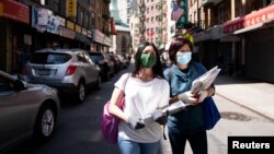FILE Shirley Ng (l) , a volunteer with the Chinatown Block Watch neighborhood patrol group, distributes Chinese newspaper along a street in Chinatown during the outbreak of the coronavirus disease (COVID-19) in New York City, New York, U.S., May 17, 2020.
