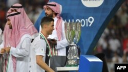 Pemain depan Juventus, Cristiano Ronaldo, berjalan melintasi trofi Supercoppa Italiana, setelah final melawan AC Milan di Stadion King Abdullah Sports City di Jeddah, 16 Januari 2019.