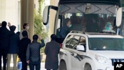 Workers wave to the team of experts from the World Health Organization who ended their quarantine and prepare to leave the quarantine hotel by bus in Wuhan in central China's Hubei province on Thursday, Jan. 28, 2021. (AP Photo/Ng Han Guan)