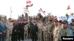 PM Iraq, Haider al-Abadi (tengah) mengangkat bendera Irak saat ia mengumumkan kemenangan atas Islamic State di Mosul, Irak, 10 Juli 2017 (courtesy: Kantor PM Irak/Rilis via REUTERS)