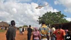 Residents look at a police helicopter patrolling near the closed house, where Italian volunteer for the Italian charity Africa Milele lived before she was seized, in Chakama trading centre of Magarini, Kilifi County, Kenya Nov. 21, 2018. 