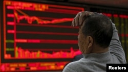 在北京一家证券交易公司，有人观看电子屏幕上的股票信息，屏幕右侧的股价一片惨绿（2016年1月4日）