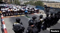 Warga Palestina melakukan ibadah sembahyang Jumat pertama dalam bulan Ramadan sementara polisi Israel berjaga di wilayah Wadi al-Joz, Yerusalem Timur (4/7).