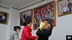 Seorang pria menggendong cucunya usai foto bersama anggota keluarga lainnya di sebuah studio foto di Beijing, China, 17 Januari 2023. (Foto: Andy Wong/AP Photo)