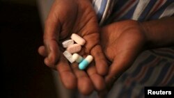 Nine-year-old Tumelo shows off antiretroviral (ARV) pills before taking his medication at Nkosi's Haven, south of Johannesburg, Nov. 28, 2014. 