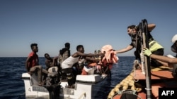 Masu agaji daga jirgin Ocean Viking suna mikawa bakin huare da suka fito Libya rigar hana nutsewa cikin ruwa lokacin da suke cetonsu a tsakiyar tekun Mediterranean