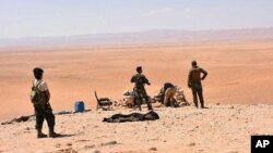 This photo released Sept 2, 2017, by the Syrian official news agency SANA, shows Syrian troops and pro-government gunmen standing guard at one of the frontline hills where they are fighting IS militants in Deir el-Zour, Syria.