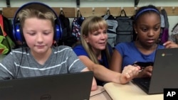 GIn this Sept. 20, 2018 photo, fifth grade teacher Heather Dalton, center, works with students Julian Ryno, left, and Ma'Kenley Burns, doing math problems on the DreamBox system at Charles Barnum Elementary School in Groton, Conn. (AP Photo/Michael Melia)