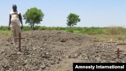 Rev Thomas Agou by the mass grave of 18 women killed by opposition forces in and around St Andrew's Cathedral in Bor in January 2014. © Amnesty International