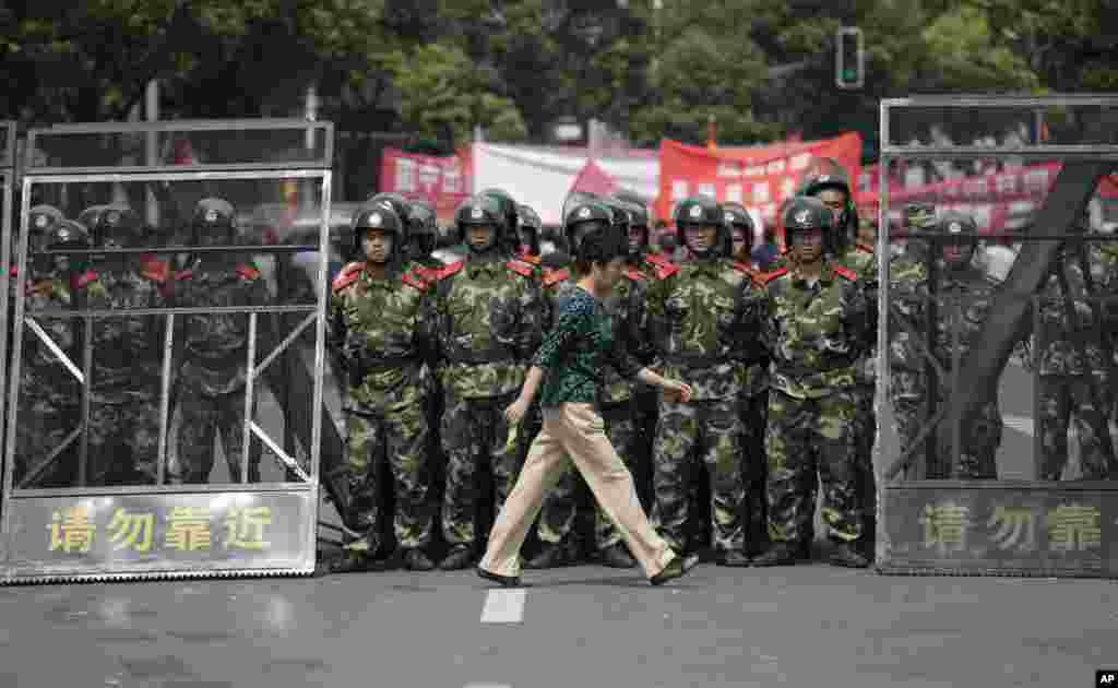 A woman walks past paramilitary police officers standing guard during anti-Japan protests near the Japanese Consulate General, Shanghai, China, September 18, 2012.