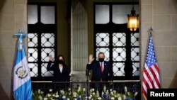 U.S. Vice President Kamala Harris and Guatemala's President Alejandro Giammattei wave as they pose for a photo on a balcony at the Palacio Nacional de la Cultura, in Guatemala City, Guatemala, June 7, 2021.