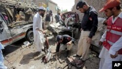 Pakistani police officers examine the site of a bomb blast in a bus stand in Matani near Peshawar, Pakistan, June 5, 2011