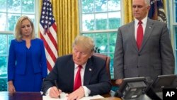 도널드 트럼프 대통령이 20일, 마이크 펜스 부통령과 커스텐 닐슨 국토안보부 장관이 지켜보는 가운데 불법 이민자 가족의 격리를 막는 행정명령에 서명하고 있다.