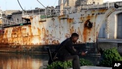 Seorang migran menggunakan telepon selularnya saat ia duduk di sebuah dok di pelabuhan Valetta, Malta, 2 Februari 2017 (foto: AP Photo/Gregorio Borgia)