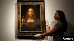 FILE - Members of Christie's staff pose for pictures next to Leonardo da Vinci's "Salvator Mundi" painting which will be auctioned by Christie's in New York in November, in London, Britain, Oct. 24, 2017. 