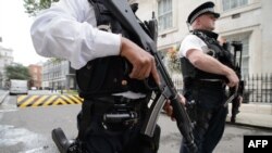 Armed police officers hold guns as they stand on Downing Street, in central London, Aug. 29, 2014. 