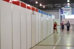 FILE - A woman goes into a cabin at a vaccination center at the Dresden Fair, in Dresden, Germany, July 29, 2021.