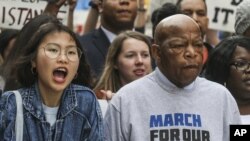 Legislator John Lewis, kiri, memimpin unjuk rasa melalui jalan-jalan di Atlanta pada 24 Maret 2018. Para peserta berasal dari Atlanta dan dari seluruh negeri berunjuk rasa memprotes kekerasan bersenjata dan mendukung aturan penggunaan senjata yang lebih ketat.