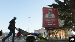 FILE - A man pushes a wheelbarrow past a billboard for Zambian presidential candidate Fred M'Membe in Lusaka, Zambia, July 5, 2021.