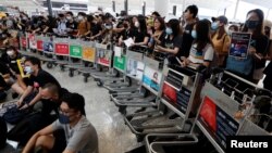 在香港机场，示威者们站在由手推车组成的路障前示威。(2019年8月13日)