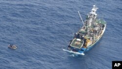 This photo released by the New Zealand Defence Force shows a wooden dinghy, left, carrying seven survivors from a missing ferry and a fishing boat in the Pacific Ocean, Jan. 28, 2018. 