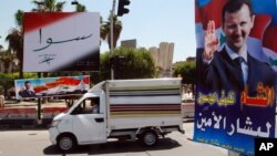 FILE - A vehicle drives past campaign posters for a presidential election in Damascus, Syria, May 12, 2014. Opposition politicians argue upcoming parliamentary elections are an effort by Assad to project a political legitimacy he doesn’t have.