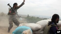 FILE - An Afghan National Army soldier (L) shouts at Taliban fighters, after firing a rocket towards Taliban positions, on the outskirts of Kunduz, northern Afghanistan, April 16, 2016.
