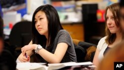 FILE - Sally Kim takes notes during a physics class at Columbia Independent School in Columbia, Mo., Feb. 27, 2012. Kim's parents, who live in South Korea, sent her to live with relatives in Columbia for a better education that provides more collegiate op