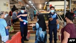 មន្ត្រី​សន្តិសុខ​ពិនិត្យ​មើល​សីតុណ្ហភាព​របស់​អ្នក​ចូល​ក្នុង​ផ្សារ​មួយ​កន្លែង នៅ​ក្នុង​ក្រុង Penang ប្រទេស​ម៉ាឡេស៊ី កាលពី​ថ្ងៃទី២៩ ខែឧសភា ឆ្នាំ២០២០។