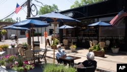 Carole Friedler, center, sits with a friend at an outdoor table while dining at Auray Gourmet, Tuesday, June 9, 2020, in Larchmont, N.Y. The outdoor tables enable the restaurant to serve more customers as social distancing rules apply. Counties…