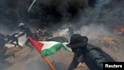 Des manifestants palestiniens tentent de se mettre à couvert quand la police lance du gaz lacrymogène à la frontière entre Israël et Gaza, le 14 mai 2018.
