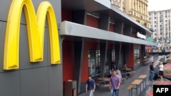 People walk in front of a closed McDonald's restaurant, the first to be opened in the Soviet Union in 1990, in Moscow, August 21, 2014. 