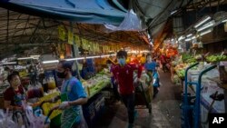 បុរស​ដែល​ពាក់​ម៉ាស់​អូស​រទេះ​កាត់​ផ្លូវ​ចង្អៀត​មួយ​នៅ​ក្នុង​ផ្សារ​មួយ​នៅ​ក្នុង​ក្រុង​បាងកក ប្រទេស​ថៃ កាលពី​ថ្ងៃទី៩ ខែមេសា ឆ្នាំ២០២០។