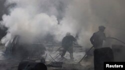 Civil defense members try to put out a fire at a site hit by what activists said was a barrel bomb dropped by forces loyal to Syria's President Bashar al-Assad in the Qadi Askar neighborhood of Aleppo, March 5, 2015. 