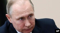 Russian President Vladimir Putin listens during a meeting in Moscow, Russia, Friday, April 13, 2018. The Kremlin says Russian President Vladimir Putin and French President Emmanuel Macron have agreed to coordinate their actions to avoid further military escalation in Syria.