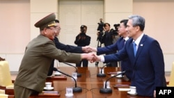 Penasihat keamanan nasional kepresidenan Korea Selatan Kim Kwan-Jin (kanan), dan Menteri Unifikasi Hong Yong-Pyo (kedua dari kanan) berjabatan tangan dengan pejabat tinggi militer Korea Utara Hwang Pyong-So (kiri) dan pejabat tinggi urusan Korea Selatan Kim Yang-Gon (kedua dari kiri) dalam pertemuan di desa Panmunjom (22/8). 
