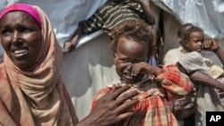 Nasteho Hassan Mohyadin, 3, and her mother Farhid Ali Mohamed sit outside their small makeshift tent in a camp for those displaced by last year's famine or by conflict, in Mogadishu, Somalia, Jan. 19, 2012.