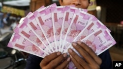 FILE - An Indian man displays new currency notes of 2000 Indian rupee in Ahmadabad, India, Nov. 11, 2016. 