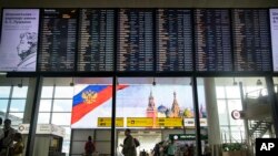Passengers walk past a departure board at Sheremetyevo international airport in Moscow, Russia, July 8, 2019. 