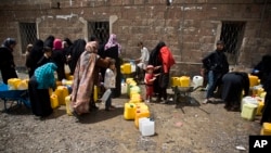 FILE - Women and children wait to fill buckets with water from a public tap amid an acute shortage of water, in Sana'a, Yemen, May 9, 2015.