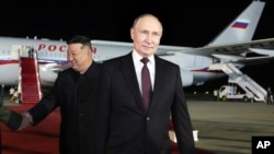 Ruski predsjednik Vladimir Putin, desno, šeta dok se lider Sjeverne Koreje Kim Džong Un rukuje s ruskom delegacijom tokom njihovog sastanka na međunarodnom aerodromu Pjongjang Sunan izvan Pjongjanga, Sjeverna Koreja, rano u srijedu, 19. juna 2024.