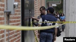 Federal agents inspect bullet impacts at a crime scene in Ocotlan, Mexico, where 10 people were killed in a gunfight when suspected gang members ambushed a police convoy, March 20, 2015.