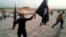 FILE - An Islamic State fighter holds the extremist group's signature flag and a weapon in the Iraqi city Mosul, June 23, 2014. Preparations are underway to wrest the city from IS control.